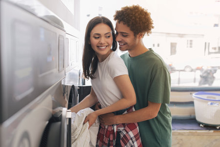 Romantic Man Hugging Wife Loading Washing Machine At Laundromat Roomの写真素材