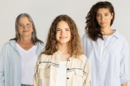 Confident smiling adult, elderly women and teen girl isolated on gray studio backgroundの写真素材