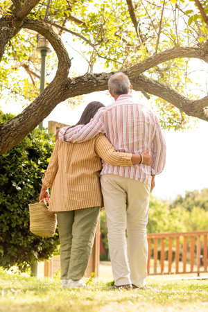 Senior european man and woman hugging, enjoys romantic date, walk in park, back, verticalの写真素材