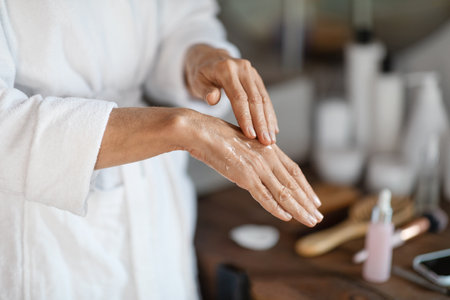Dry Skin Treatments. Mature woman applying anti-aging serum on hands at homeの写真素材