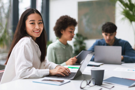 Korean Businesswoman Typing On Laptop Smiling During Corporate Meeting Indoorの写真素材