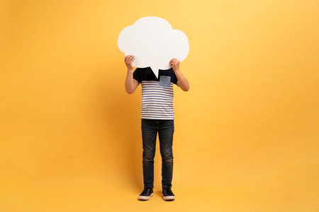 Unrecognizable casual boy holding white paper communication bubble over headの写真素材