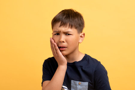 Portrait of unhealthy school aged boy touching cheek