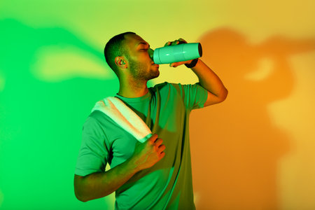 African american fitness man drinking healthy liquid in studioの写真素材
