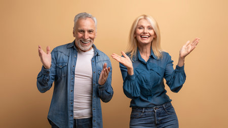 Amazed excited elderly man and woman gesturing on beige backgroundの写真素材
