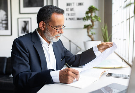 serious concentrated caucasian senior businessman in suit with contract types on computer in modern...