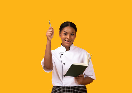 Cooking Idea. Excited Black Chef Woman Holding Cookbook And Penの写真素材