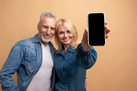 Loving elderly couple showing phone with black empty screenの写真素材