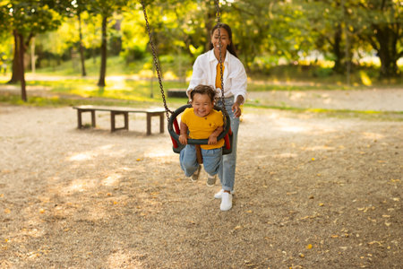 Japanese Mother Swinging Her Baby Toddler Girl on Swing Outsideの写真素材