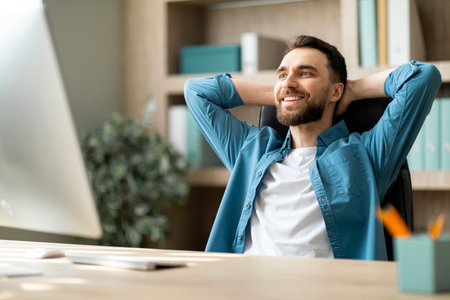Portrait Of Smiling Millennial Male Entrepreneur Relaxing At Workplace In Officeの写真素材