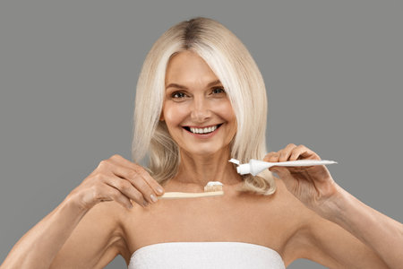 Daily Dental Care. Beautiful Mature Woman Pouring Toothpaste On Toothbrushの写真素材