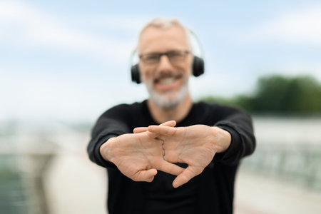 Happy senior sportsman exercising outdoor, stretching handsの写真素材