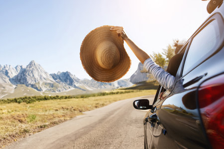Woman hand holding wicker hat from car window, copy spaceの写真素材