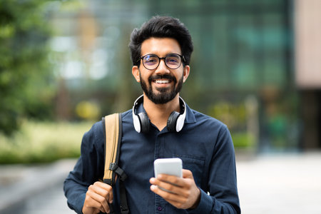 Portrait of positive hindu entrepreneur using phone outdoorの写真素材