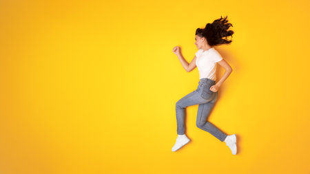 Happy Lady Running In Mid Air Looking Aside, Yellow Backgroundの写真素材