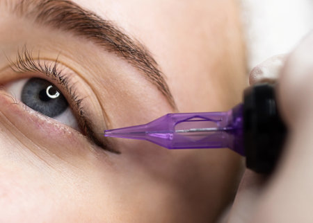 Micropigmentation Concept. Beautician doing permanent make up eyeliner procedure to young womanの写真素材