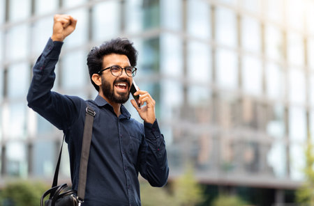 Happy young indian businessman have phone call, got great newsの写真素材
