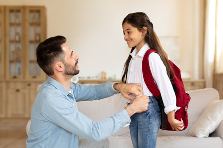 Happy father preparing daughter for first school day at homeの写真素材