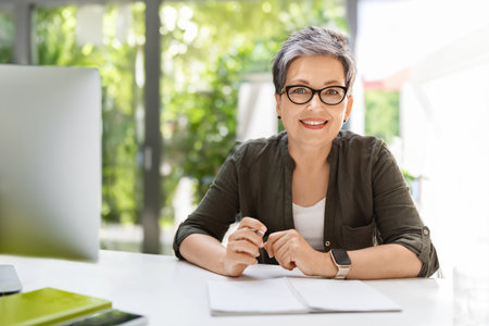 Cheerful mature woman business consultant working at officeの写真素材