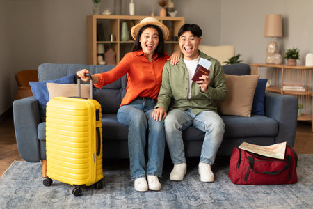 Joyful Japanese Travelers Couple Posing With Travel Tickets At Homeの写真素材