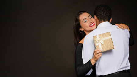 Happy beautiful brunette woman holding present and hugging boyfriendの写真素材