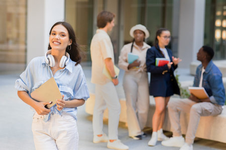 Cheerful pretty brunette lady posing over multiracial group of studentsの写真素材