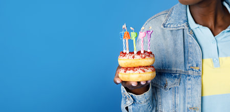 Cropped black woman holding donuts with birthday candles, copy space