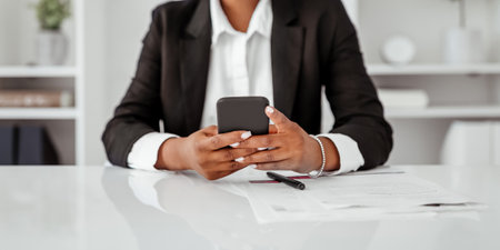 Communication in business. Cropped of black businesswoman using cellphone, sitting in office, panoramaの写真素材