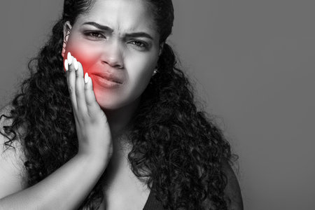 Black and white photo of latin chubby lady suffering from tooth pain, touching sore red zone on her cheek, copy spaceの写真素材