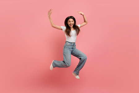 Cheerful Beautiful Teen Girl Jumping In Air Over Pink Studio Background