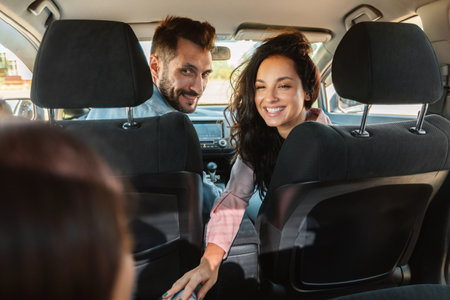 Family of three enjoying car ride during road trip on weekend, young parents and their daughter...