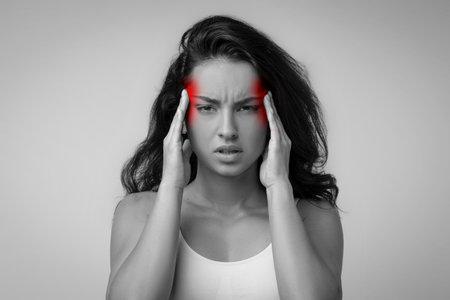 Irritated upset middle eastern millennial woman in pain rubbing templesの写真素材