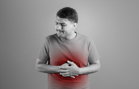 Sick brazilian man having stomach ache, touching his abdomen with red inflamed zone, black and white photoの写真素材