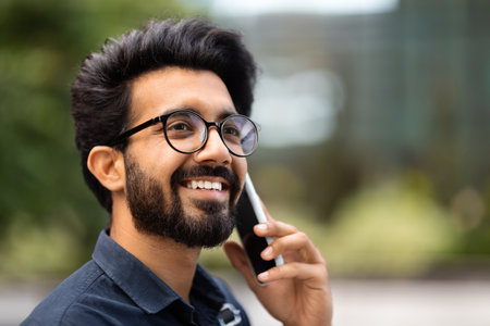 Handsome young indian man talking on cellphone while walking