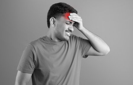 Black and white photo of brazilian man in pain touching forehead, having headache, studio backgroundの写真素材