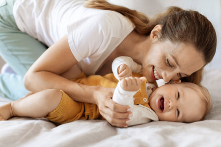 Happy young mother and toddler child bonding in bedの写真素材