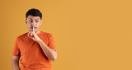 Handsome brazilian man keeping finger on lips, showing silence gesture, looking aside at copy space...