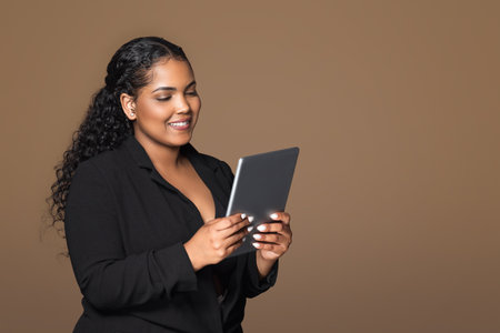 Cheerful brazilian businesswoman using digital tablet, copy space. Device for business, investment and startupの写真素材