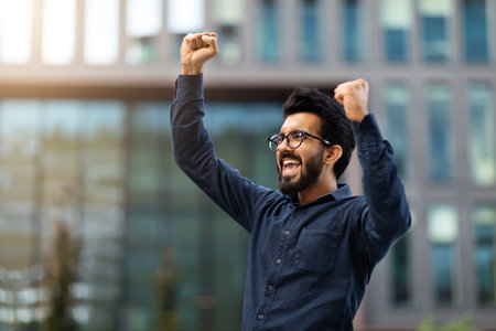 Portrait of thrilled young indian guy over business buildingの写真素材