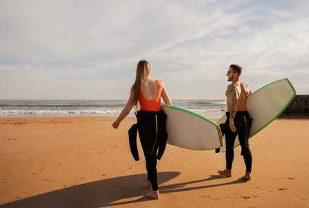 Watersports Concept. Young Couple With Surfboards Going Into The Oceanの写真素材