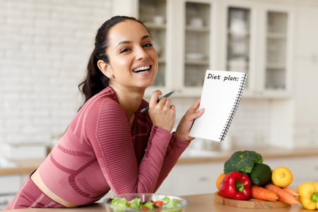 Happy Fit Young Lady Writing Diet Plan In Notebook Indoorの写真素材