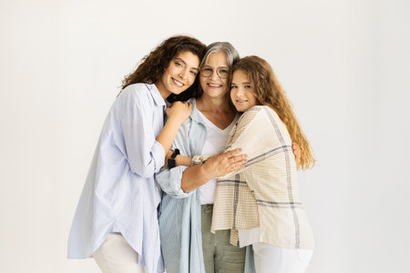 Happy caucasian senior, mature and teen women hugging, enjoy love on white wall background