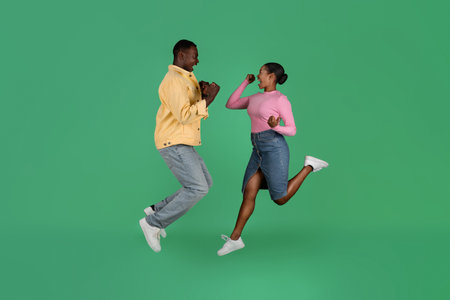 Thrilled african american millennial man and woman gesturing and jumpingの写真素材
