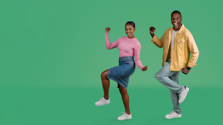 Excited happy young black couple celebrating success on greenの写真素材