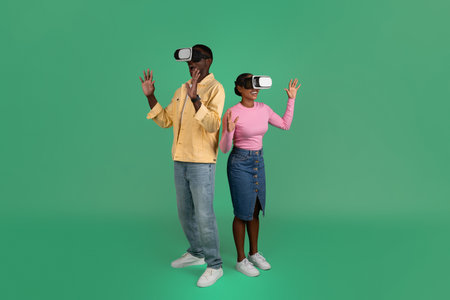 Millennial black guy and woman using VR glasses, green backgroundの写真素材