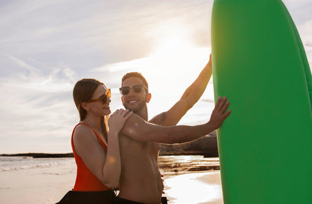 Sporty Surfers Couple Having Fun While Surfing Together On The Beachの写真素材