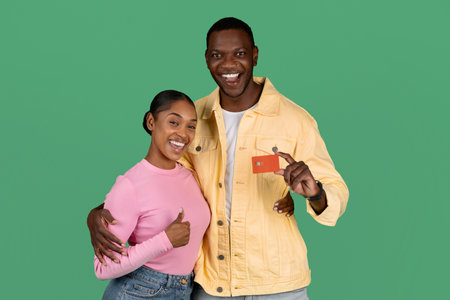 Excited millennial black man and woman holding bank credit card