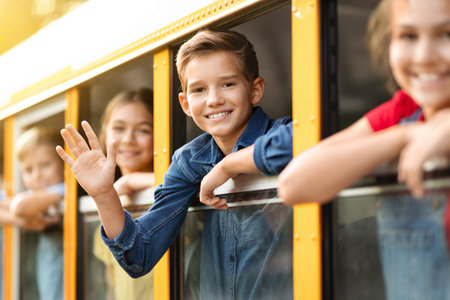 Group Of Pupils Peeking Out Of School Bus Window And Waving Handsの写真素材