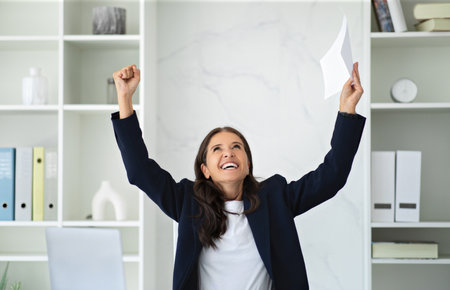 Super happy mature woman executive raising hands up