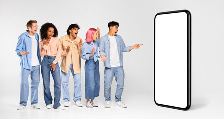 Online offer. Excited international friends pointing at huge blank smartphone for mockup, panorama